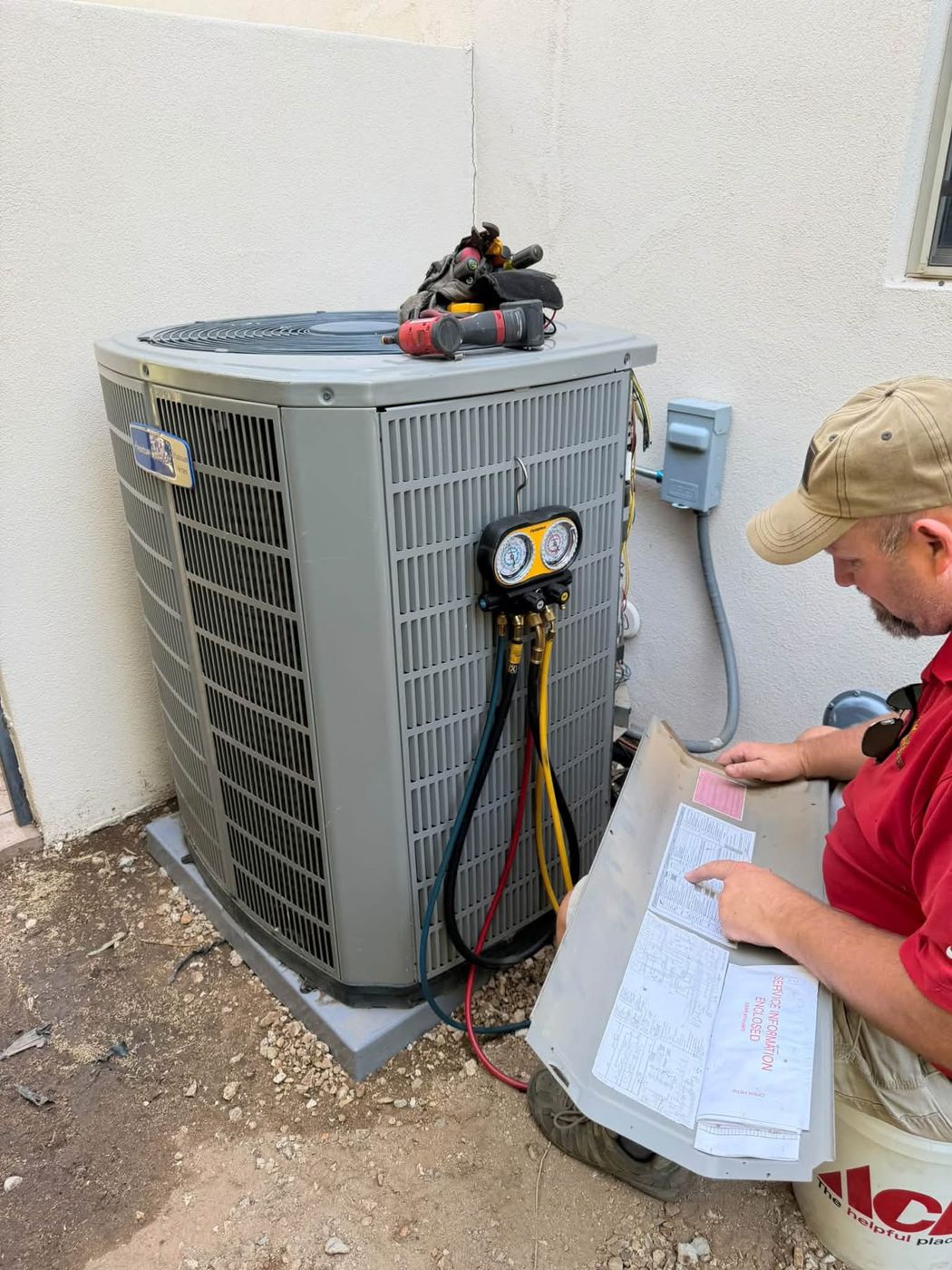 Noble technician checking refrigerant gauges on an outdoor AC unit